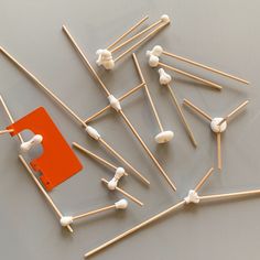 a group of toothpicks and matches on a gray surface with an orange square in the middle