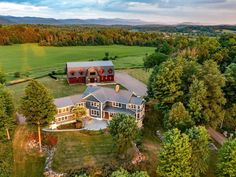 an aerial view of a large house surrounded by trees and grass with mountains in the background