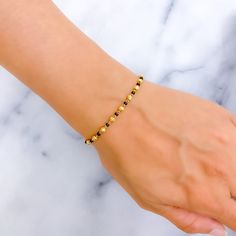 This dainty alternating 22k gold bracelet, weighing 4.3 grams, presents a polished yellow gold finish, elegantly complemented by black beads. The design, featuring a bracelet length of 7 inches, includes 0.6" adjustable links for a customized fit, secured with a hook lock. Ideal for those who value subtle elegance and refined detail, this piece harmoniously blends the luster of gold with the sophistication of black beads. It offers a versatile and stylish accessory, perfect for adding a touch of Elegant Gold Bracelet Simple, Black Beads Bracelet Gold, Hand Mangalsutra Bracelet, Black Bead Bracelet, 22k Gold Bracelet, Black Pearl Bracelet, Mangalsutra Bracelet, Mangalsutra Chain, Gold Bracelet Simple