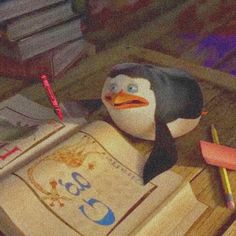 a penguin sitting on top of a pile of books next to a pencil and eraser