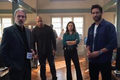 three men and two women standing in a room with wood flooring, one man is looking at the camera