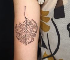 a woman's arm with a leaf tattoo on it