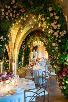 an outdoor dining area with tables and chairs covered in floral arrangements, lit by candles