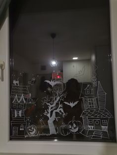 the window is decorated with black and white halloween scenes, bats, pumpkins and trees