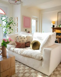 a living room filled with white furniture and lots of flowers on top of the couch