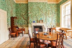 a living room filled with furniture and walls covered in green wallpaper, next to a fire place