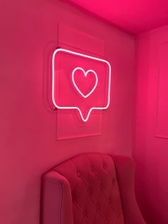 a pink room with a chair and neon sign on the wall that says i love you