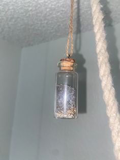 a glass jar filled with sand hanging from a rope on the ceiling in a room