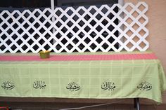 a table with a green cloth on it in front of a white latticed fence