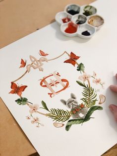 someone is painting letters with flowers and leaves