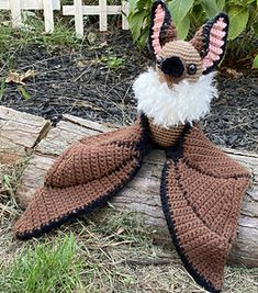 a crocheted stuffed animal sitting on top of a log