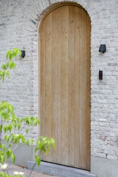 a large wooden door sitting next to a white brick building