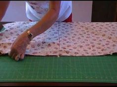 a person is cutting fabric on a table with scissors and a green mat in front of them