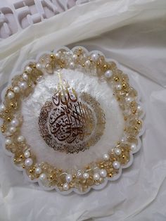 a white and gold plate with an arabic calligraphy on the inside is surrounded by pearls