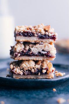 three bars stacked on top of each other with crumbled toppings and a glass of milk in the background