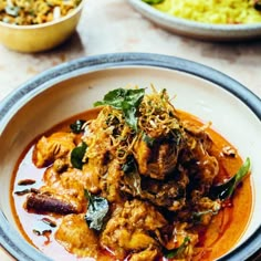 two bowls filled with food sitting on top of a table next to other plates full of food