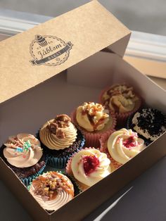 a box filled with lots of different types of cupcakes