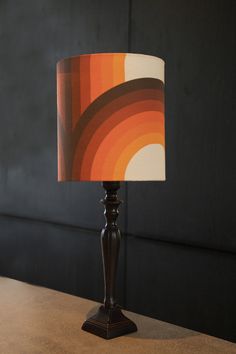 a lamp that is sitting on top of a table in front of a black wall