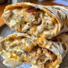 two chicken burritos on a plate covered in cheese