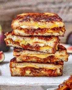 three grilled cheese sandwiches stacked on top of each other next to some sliced fruit