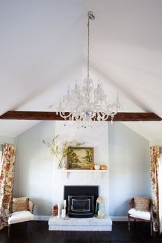 a living room filled with furniture and a chandelier hanging from the ceiling over a fire place