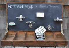 an old wooden box with metal items in front of a blackboard that says artisan soap