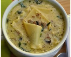 a white bowl filled with soup on top of a wooden table