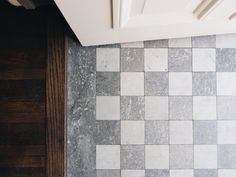 a white and grey tiled wall next to a wooden door