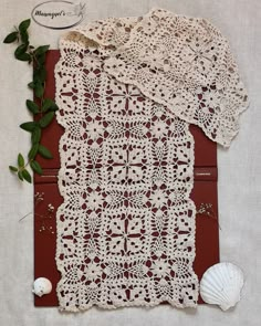 crocheted doily and seashells are laid out on a piece of cloth