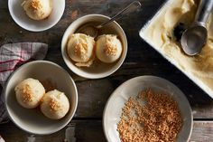 three bowls filled with ice cream on top of a wooden table next to two spoons