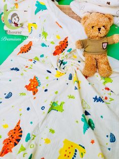 a teddy bear sitting on top of a bed next to sheets and blankets with animals