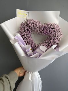 a person holding a bouquet of flowers in the shape of a heart