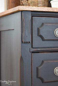 an old dresser painted in dark gray with wood top and drawer pulls on the bottom