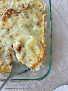 a casserole dish with meat and cheese in it, on a white cloth