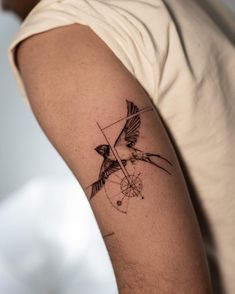 a tattoo on the arm of a man with a bird and arrow in its beak