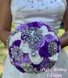 the bride's bouquet is made up of purple and white roses, brooches, and crystals