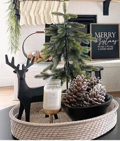 a christmas tree in a basket with pine cones and candles on the table next to it