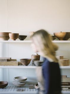 a woman standing in front of shelves filled with bowls