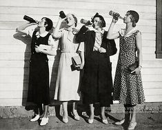 three women standing next to each other drinking from bottles