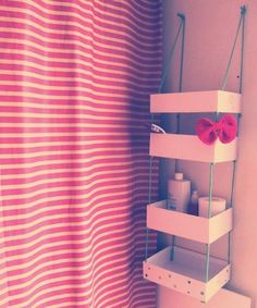 a bathroom with pink and white striped shower curtain next to a shelf holding toiletries