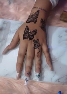 a woman's hand with butterfly tattoos on it