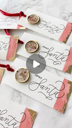 four handmade place cards with red ribbon and gold foil on them, sitting next to each other