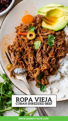 a white plate topped with shredded meat and rice next to an avocado slice