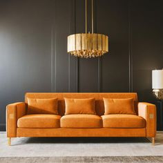 an orange couch in front of a black wall with a chandelier hanging above it