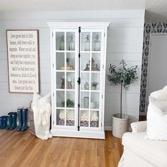 a white china cabinet with glass doors in a living room