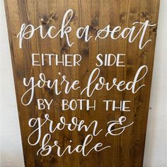 a wooden sign that says pick a seat either side you're loved by both the groom and bride