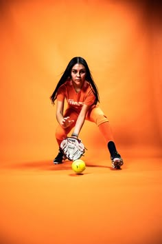 a girl in an orange shirt is playing with a tennis racket and ball on an orange background