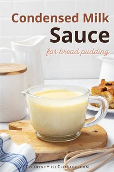 a glass bowl filled with sauce on top of a wooden cutting board next to bread