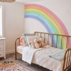 a child's bedroom with a rainbow painted on the wall and a gold metal bed frame