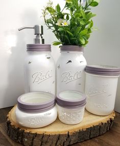 three mason jars with lavender lids are sitting on a wood slab next to a flower pot